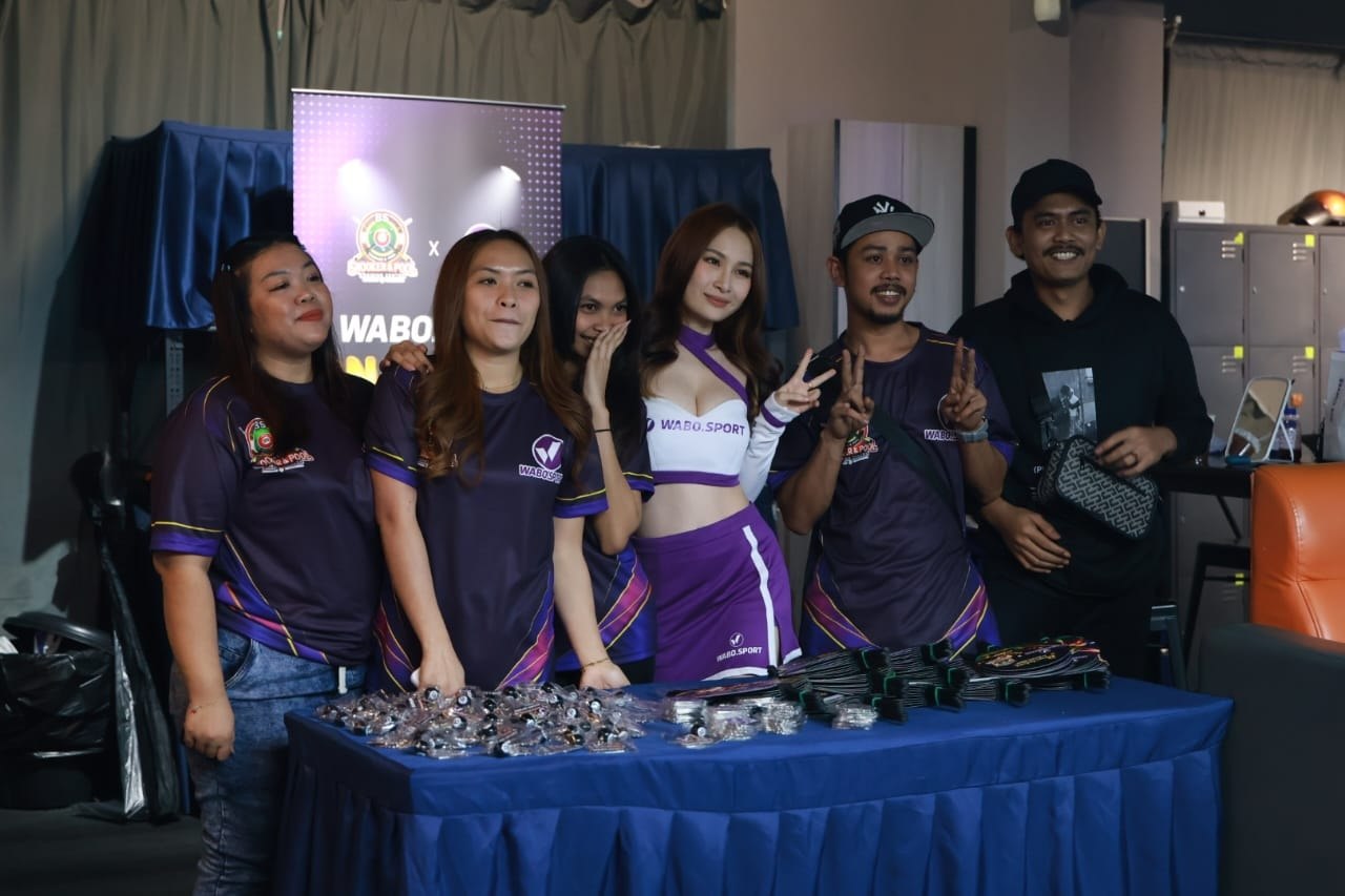 Guests posing with a WABO Sport event representative beside the championship merchandise table